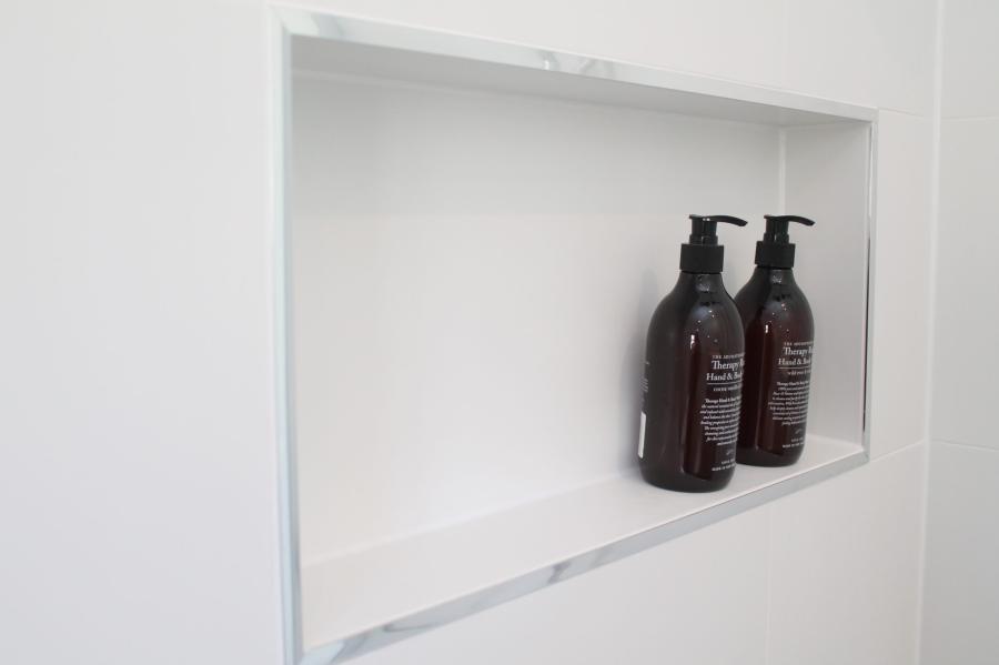 White recessed shower niche with two dark bathroom bottles