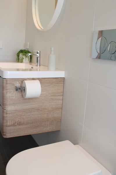Floating timber vanity and toilet in a modern white bathroom