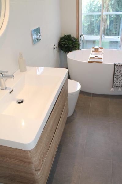 Modern bathroom with freestanding bath, timber vanity and grey floor tiles
