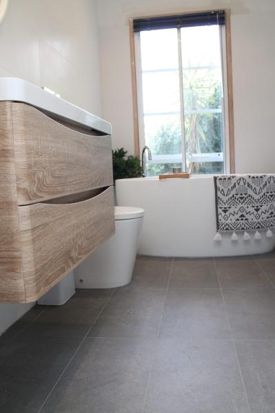 Modern bathroom with floating timber vanity, toilet and patterned Roman blind
