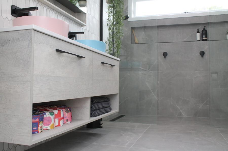 Modern grey bathroom with floating vanity, black tapware and walk-in shower