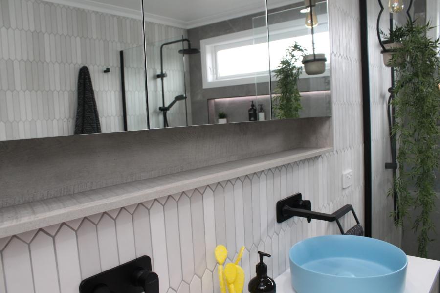 Modern bathroom vanity with blue basin, black tapware and large mirror