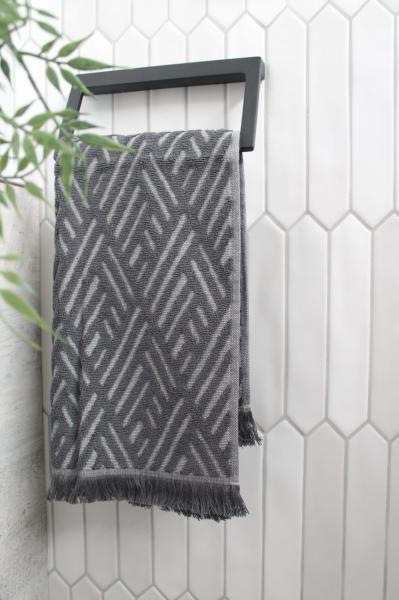 Grey patterned towel on a black rail against white vertical bathroom tiles