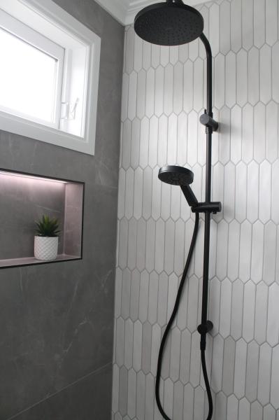 Modern walk-in shower with black rain shower, white wall tiles and recessed niche