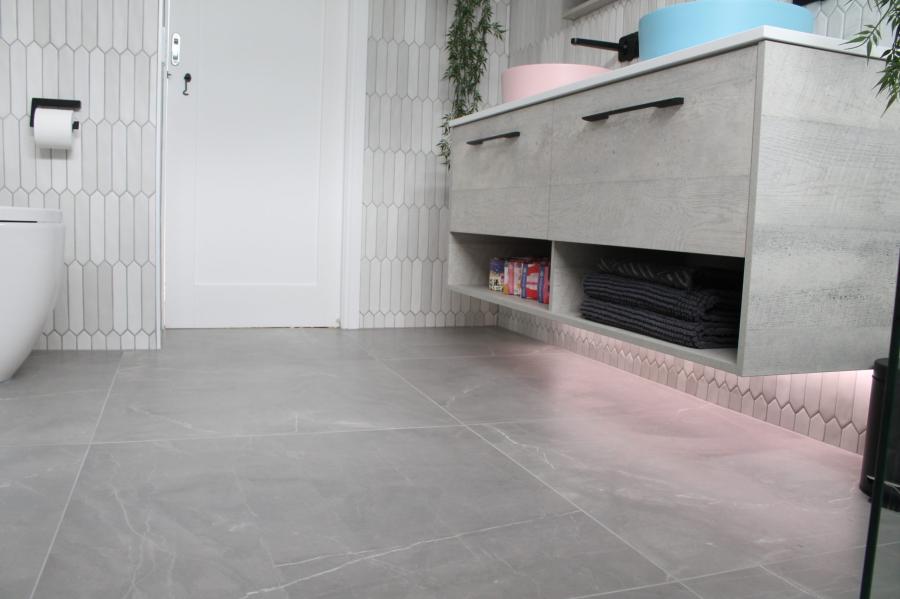 Modern bathroom with grey floor tiles, floating vanity and under-cabinet lighting