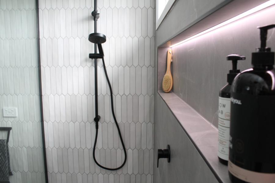Modern shower with white textured wall tiles and recessed shelf with ambient lighting