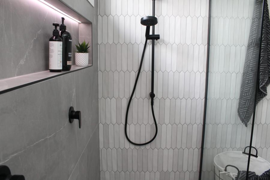 Walk-in shower with white feature tiles, recessed niche and black shower fittings