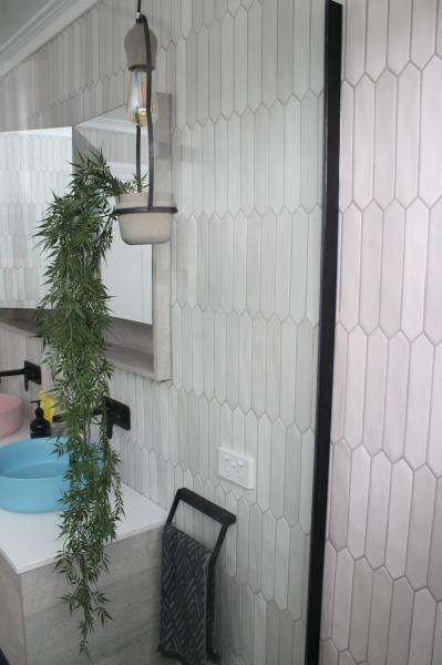 Modern bathroom vanity with round basin, wall mirror and vertical white feature tiles