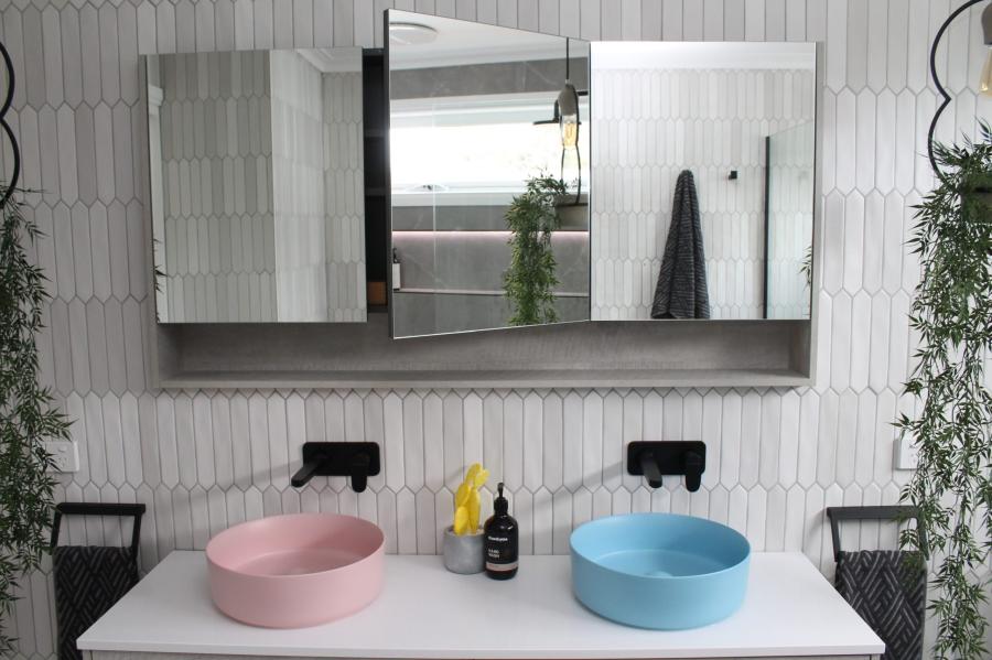 Double vanity bathroom with pink and blue basins, mirrors and textured white wall tiles