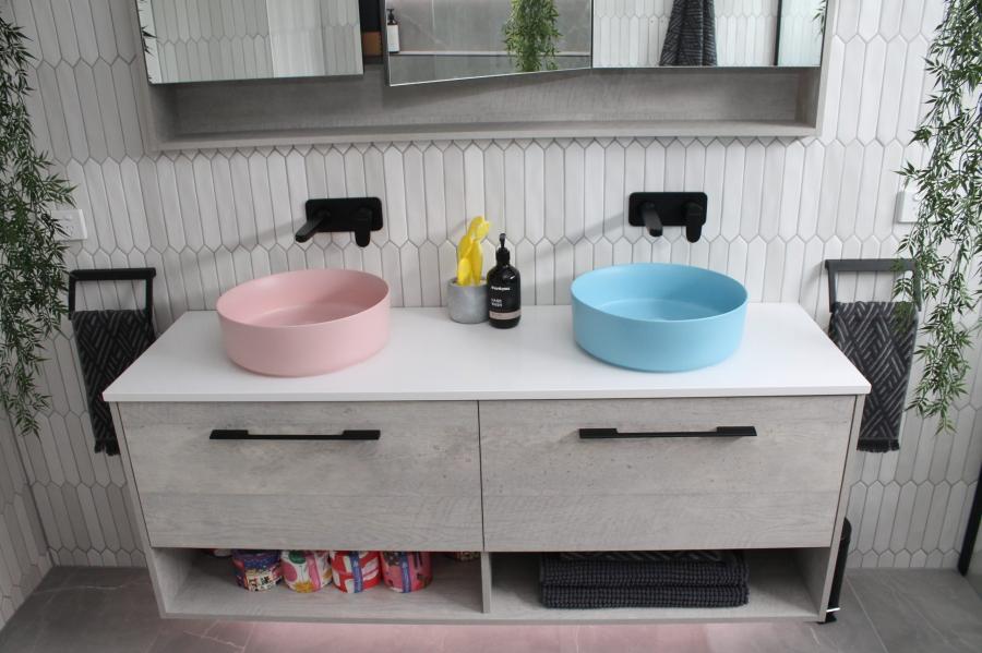 Double vanity bathroom with pink and blue basins, white cabinetry and black tapware