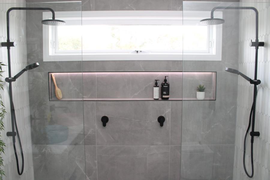 Modern dual shower with grey tiles, glass screen and recessed niche