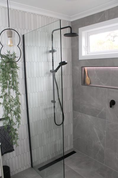 Modern walk-in shower with frameless glass, black tapware and grey wall tiles
