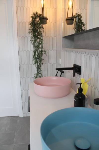 Pink and blue vessel basins on a modern bathroom vanity with textured white wall tiles