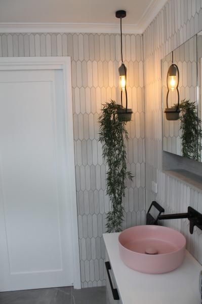 Pink vessel basin with black tapware in a white tiled modern bathroom