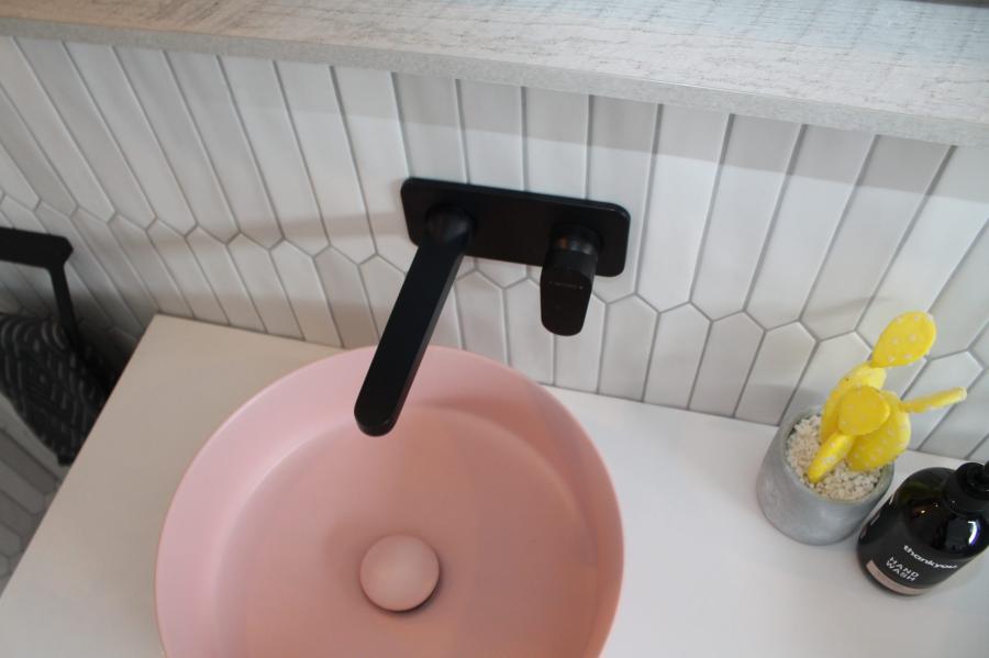 Round pink basin with matte black wall-mounted tap on a white vanity