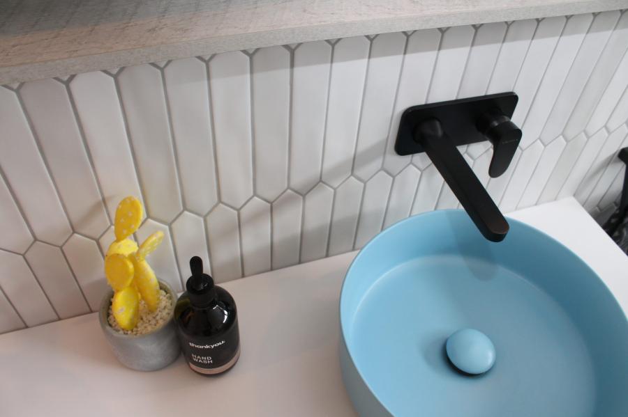 Pastel blue basin with black tapware on vanity against white feature wall tiles