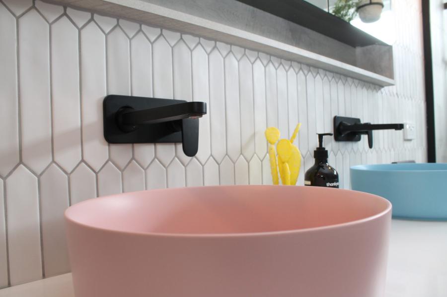 Pink vessel basin on tiled bathroom vanity with black wall-mounted tapware