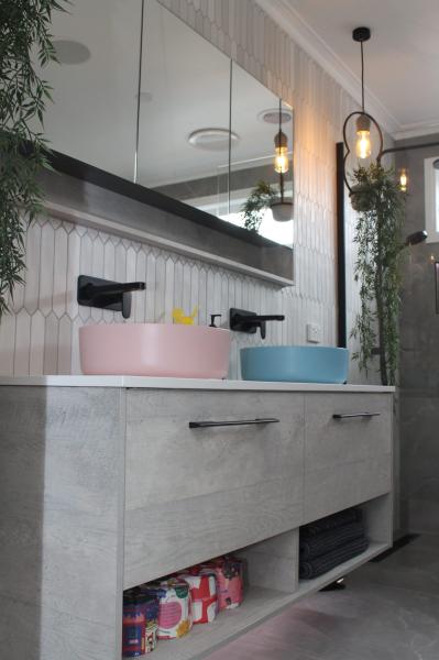 Modern bathroom vanity with pink and blue basins, mirrored cabinet and pendant lighting