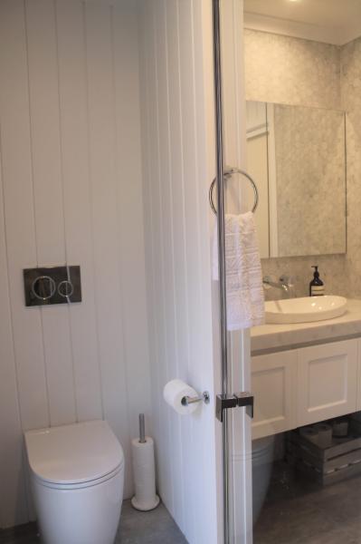 Compact white bathroom with toilet, vanity and shower area behind a partially open door