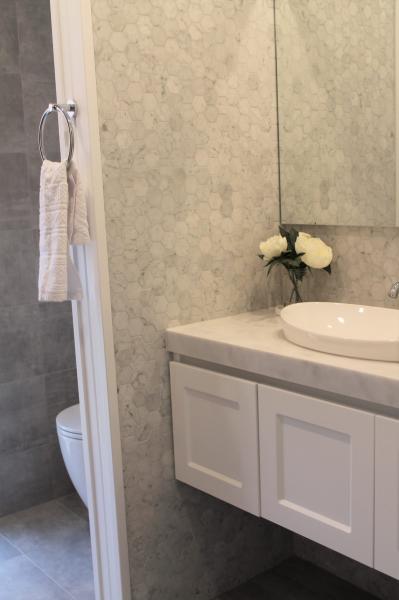 White bathroom vanity with vessel basin beside a shower in a modern tiled bathroom