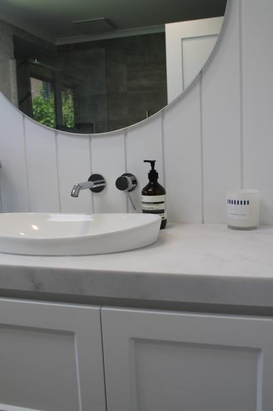 White bathroom vanity with round basin, circular mirror and matte black accessories