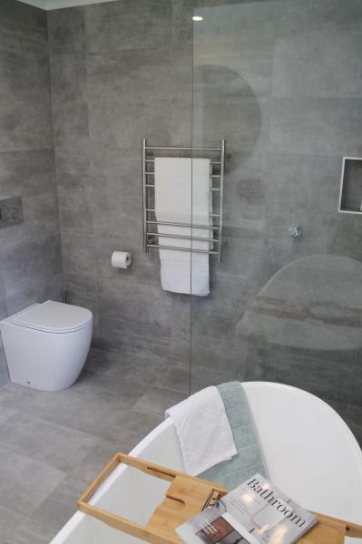 Modern grey tiled bathroom with freestanding bath, glass shower screen and wall-hung towel rail