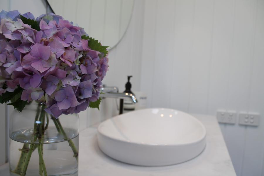 White vessel basin on vanity beside purple flowers in a modern bathroom
