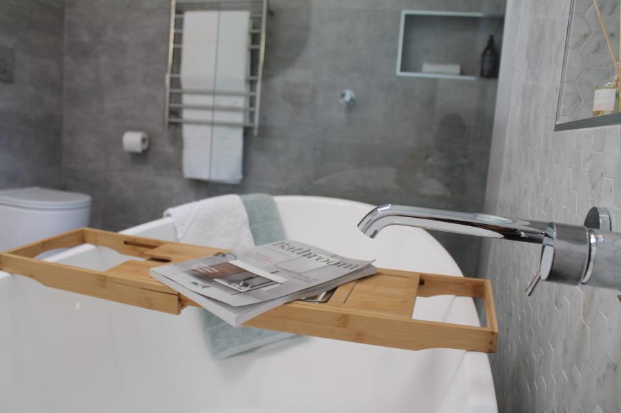 Freestanding bath with timber caddy in a modern grey tiled bathroom