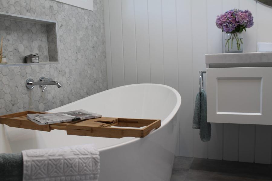 Freestanding bath with timber caddy beside a wall-hung vanity in a modern grey bathroom