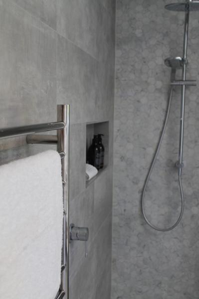 Grey tiled walk-in shower with built-in niche and chrome towel rail