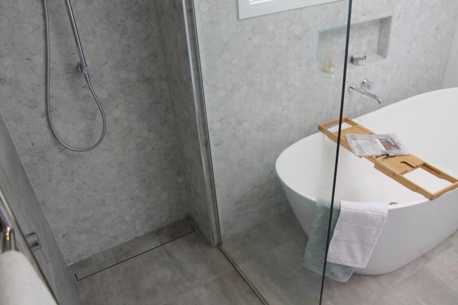 Modern grey tiled bathroom with walk-in shower and freestanding bath