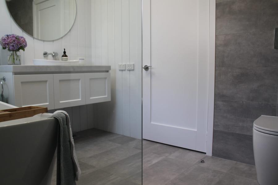 Modern bathroom with floating vanity, round mirror and grey tiled shower wall