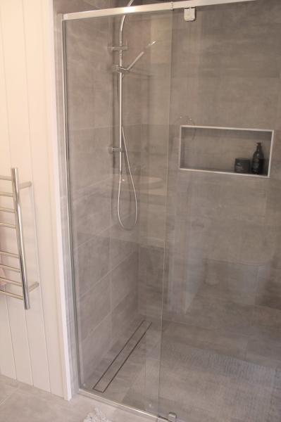 Frameless glass walk-in shower with grey tiles and recessed niche