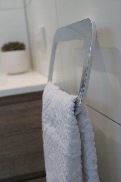 White towel hanging on a chrome rail in a modern tiled bathroom
