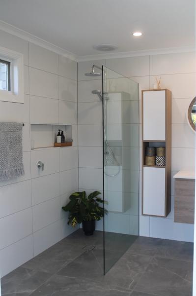 Modern white tiled walk-in shower with frameless glass screen and recessed niche