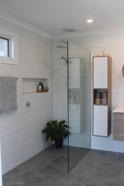 Modern walk-in shower with frameless glass screen, recessed niche and white tiled bathroom