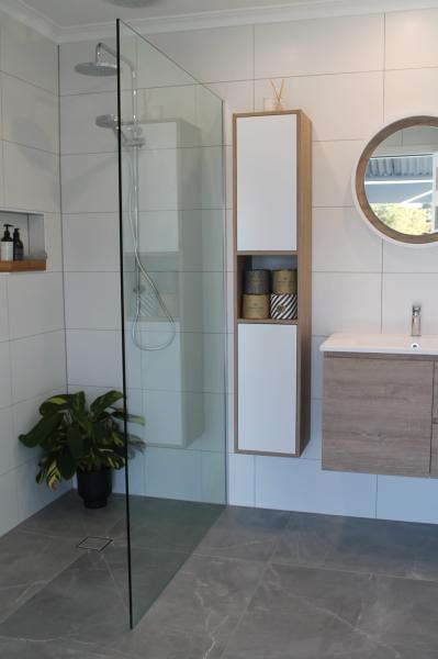 Modern white tiled bathroom with frameless glass shower, timber vanity and round mirror