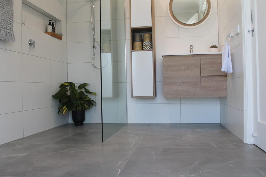 Modern white bathroom with walk-in glass shower, wall-hung vanity and grey floor tiles