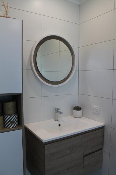 Modern bathroom vanity with round mirror, white basin and built-in storage