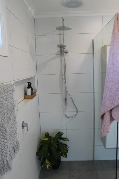 Modern tiled shower with niche shelf, chrome shower head and pink towel