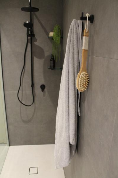Modern grey tiled walk-in shower with black shower set and hanging towel