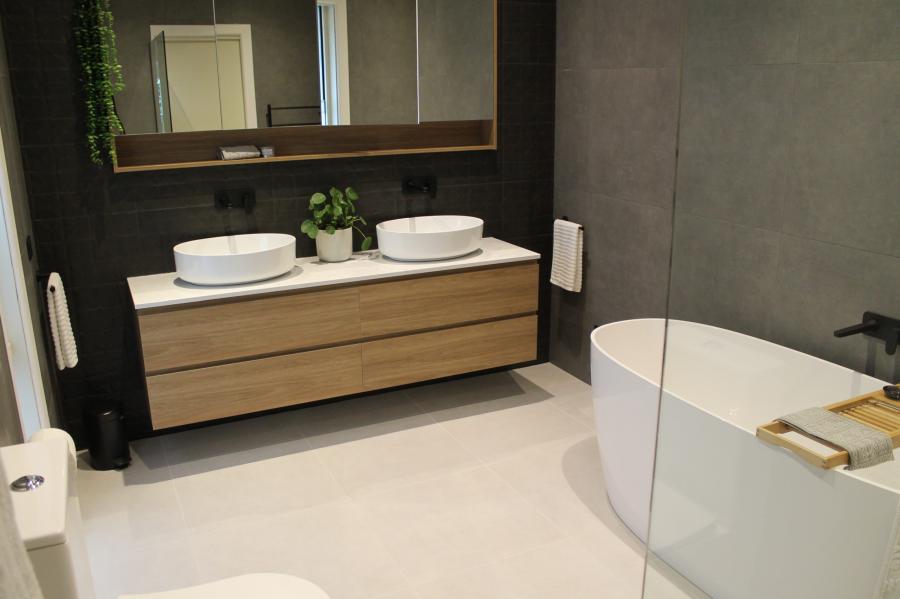 Modern bathroom with double vanity, freestanding bath and large grey wall tiles