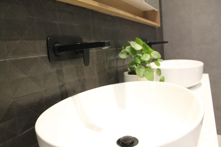 White vessel basin with black wall-mounted tap in a modern bathroom