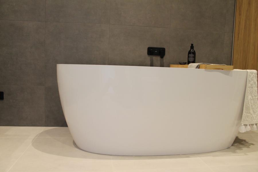 Modern white freestanding bath against grey tiled bathroom wall