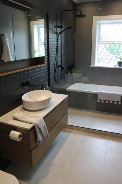 Modern grey bathroom with floating vanity, vessel basin, bath and black framed shower screen