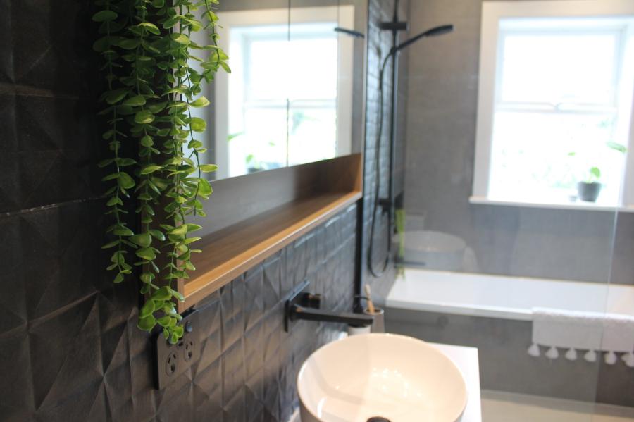 Modern grey bathroom with vessel basin, timber shelf, black tapware and freestanding bath