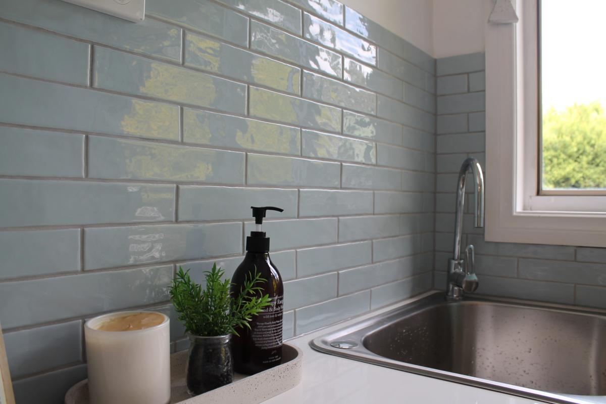 Modern kitchen sink with grey subway tiles and black dispenser