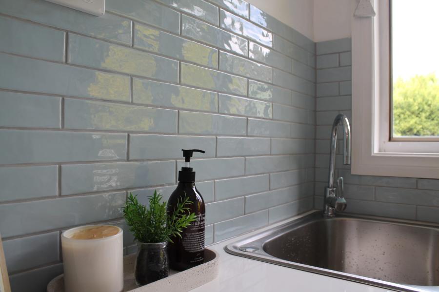 Modern kitchen sink with grey subway tiles and black dispenser
