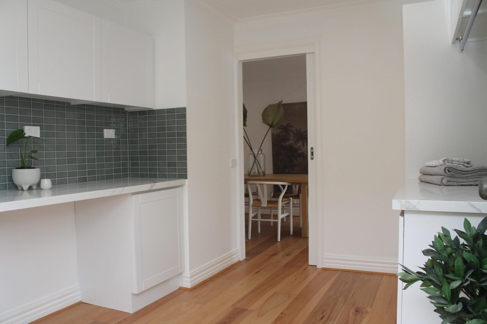 Modern laundry room with white cabinetry and green tiling