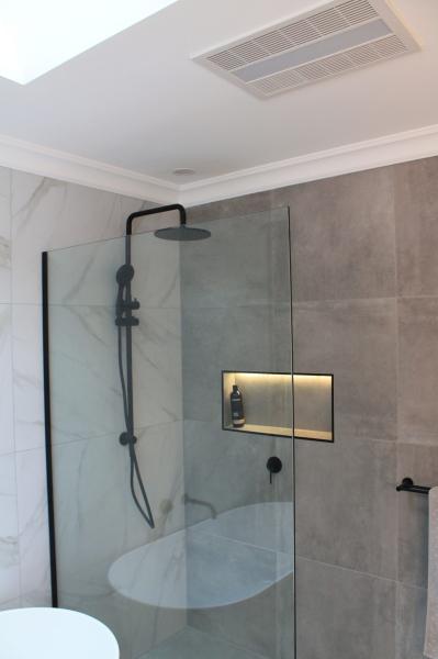 Modern walk-in shower with frameless glass, black tapware and recessed niche